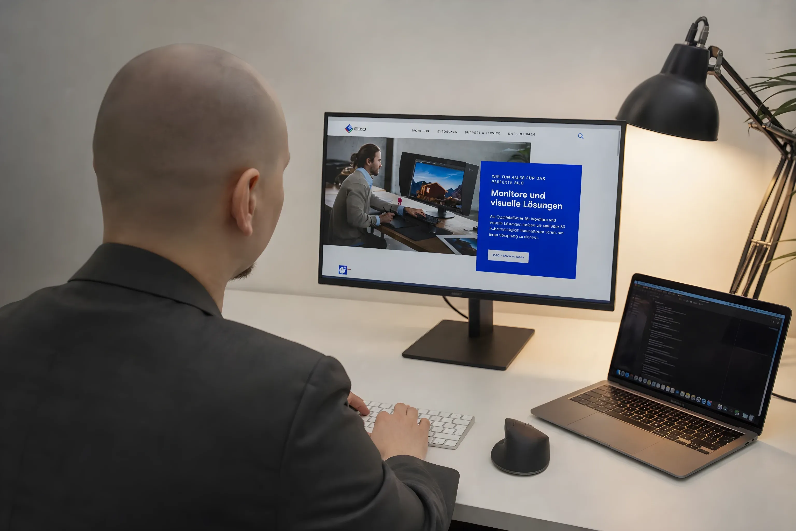 Ich am Schreibtisch, die EIZO-Website auf Laptop und externem Monitor